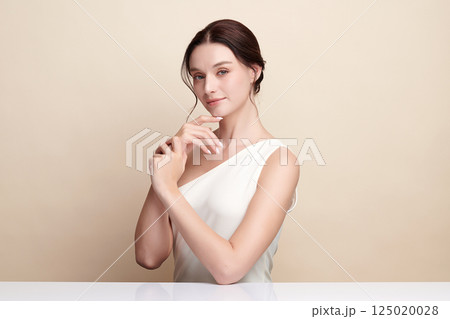 A beautiful young woman with clean, fresh skin against a beige background. Skincare, facial treatment, cosmetology, beauty, and spa. An elegant portrait of an woman. A beautiful young woman with clean, fresh skin against a beige background. Skincare, facial treatment, cosmetology, beauty, and spa. An elegant portrait of an woman. 125020028
