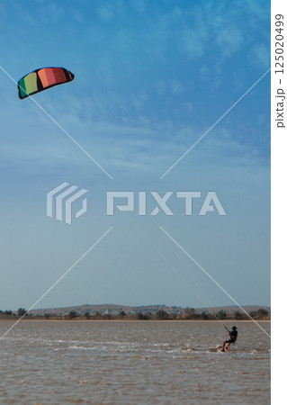 A man, an athlete, rides kitersurfing on a blue pore. Beach, active recreation. Sunset competitions, parachute, board. High quality photo A man, an athlete, rides kitersurfing on a blue pore. Beach, active recreation. Sunset competitions, parachute, board. High quality photo 125020499