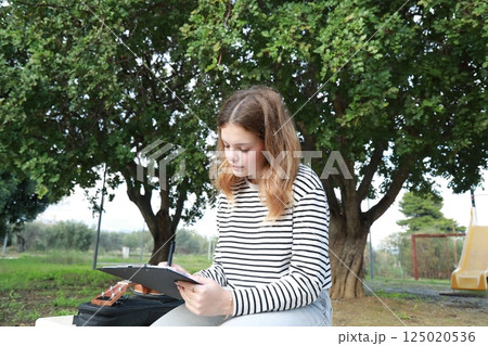 Girl Writes Musical Notes On A Sheet Music To Play Them With The Ukulele Girl Writes Musical Notes On A Sheet Music To Play Them With The Ukulele 125020536