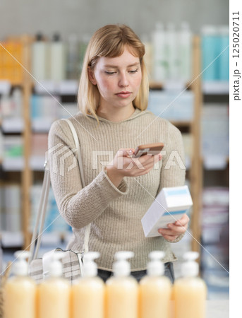 Young woman customer scanning QR-code on cream 125020711