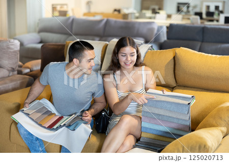 Smiling couple is choosing modern materials for furniture for their home in store 125020713