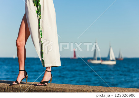Woman feet in high heels shoes on sea pier Woman feet in high heels shoes on sea pier 125020900