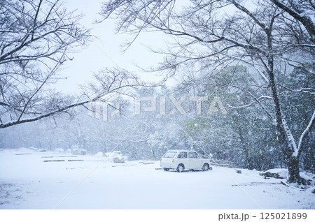 雪の降る山に一台の車 125021899