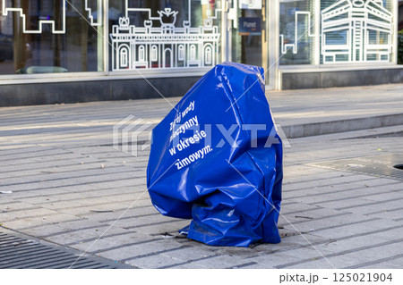 Public water fountain covered in blue winter protection wrap on city sidewalk with Polish signage Public water fountain covered in blue winter protection wrap on city sidewalk with Polish signage 125021904