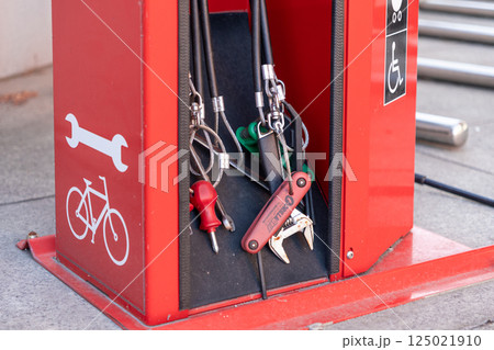 Close-up of bike repair station tools including wrenches and screwdrivers on red urban fixture 125021910