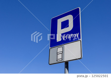 Paid parking zone traffic sign with car icon on blue and white background against clear sky on sunny day 125022501