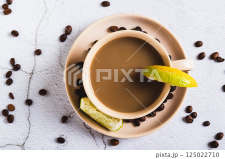 Close up of cold coffee with lime wedges in a cup on the table top view Close up of cold coffee with lime wedges in a cup on the table top view 125022710