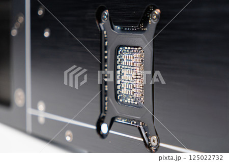 Close-up of backplate cutout revealing GPU chip layout on modern graphics card with visible electronic components Close-up of backplate cutout revealing GPU chip layout on modern graphics card with visible electronic components 125022732