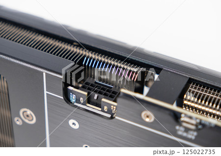 Close-up of 8-pin power connector on modern graphics card with visible heatsink fins and black metal backplate 125022735