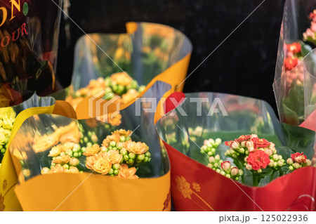 Closeup of blooming kalanchoe flowers in colorful plastic wrapping on store shelf with vibrant petals and fresh green buds in floral department 125022936