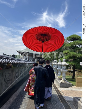 神社の庭園を歩く和傘の新郎新婦　 125023017