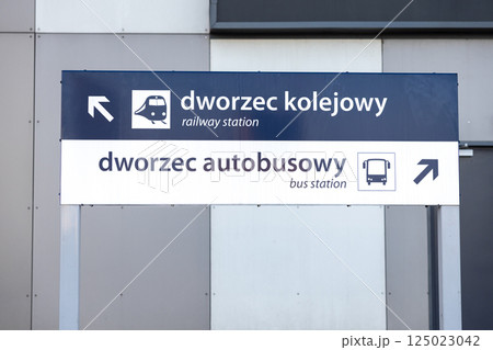 directional sign showing way to railway station and bus station with arrows and icons in polish and english language on modern grey wall background 125023042