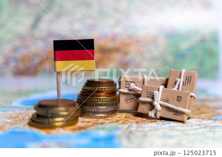 German flag near coins and parcels on a world map. World trade, export and import of goods around the world 125023715