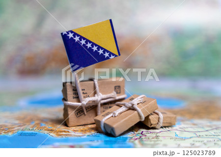 Flag of Bosnia and Herzegovina near the parcels on the world map. World trade. Exports and imports of goods. Economy of the country Flag of Bosnia and Herzegovina near the parcels on the world map. World trade. Exports and imports of goods. Economy of the country 125023789