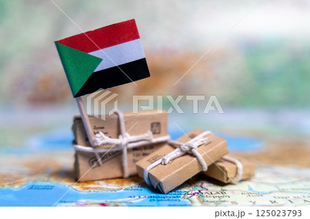 Flag of Sudan near the parcels on the world map. World trade. Exports and imports of goods. Economy of the country. Flag of Sudan near the parcels on the world map. World trade. Exports and imports of goods. Economy of the country. 125023793