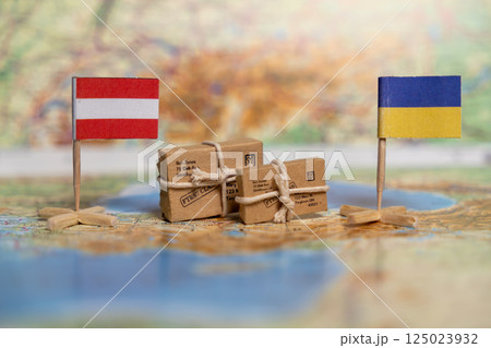 Humanitarian Aid Packages Between Austria and Ukraine Symbolized with National Flags and Parcel Boxes on World Map Background 125023932