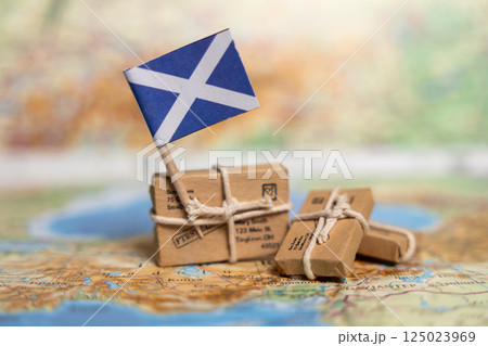 International Shipping and Delivery Services to Scotland: Small Packages with Scottish Flag on Vintage Map Background International Shipping and Delivery Services to Scotland: Small Packages with Scottish Flag on Vintage Map Background 125023969