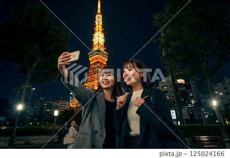 東京タワーの前でスマホで撮影する女性二人 125024166