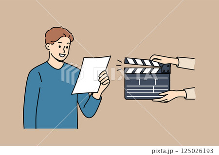 Man actor participates in casting, reading text from piece of paper, standing near clapperboard Man actor participates in casting, reading text from piece of paper, standing near clapperboard 125026193