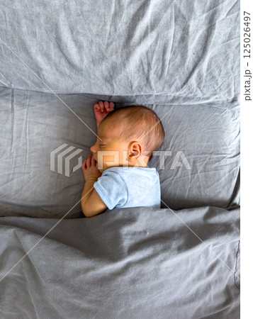 Newborn Baby Sleeping Peacefully on Bed 125026497