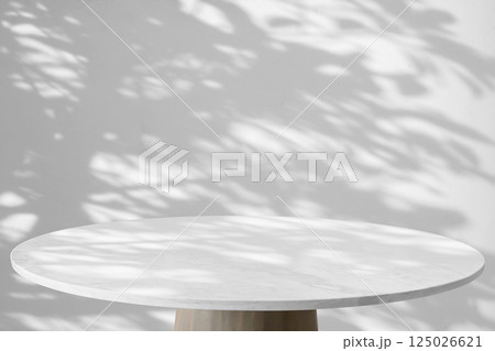 Round marble table top with tree leaves shadow drop on white wall background for mockup product display 125026621