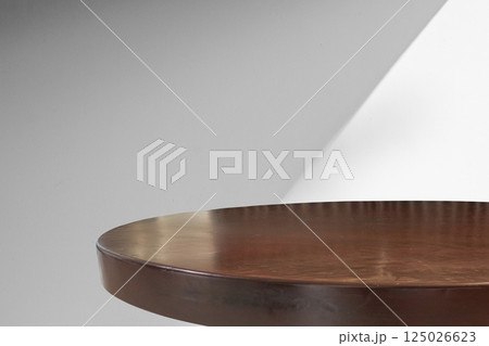 Round wood table top with abstract shadow drop on white wall background for mockup product display 125026623