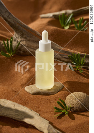 Smooth stones were buried in the desert sand, forming pedestals for the dropper bottle to stand on. The tree trunks still had grains of sand on them. Small wild plants scattered on the sand  125026994