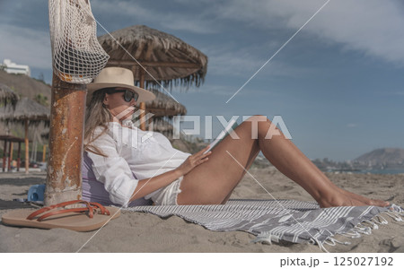 Woman relaxing on beach reading book enjoying summer meditation time 125027192