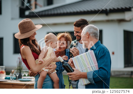 Parents welcoming their son, daughter-in-law, and baby at a family barbecue. Parents welcoming their son, daughter-in-law, and baby at a family barbecue. 125027574
