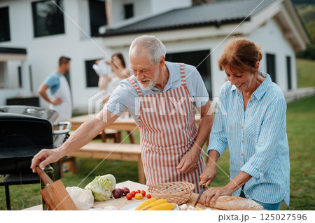 Older married couple preparing food for a family barbecue. 125027596
