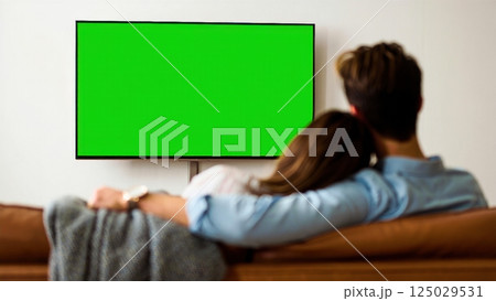 Happy couple watching tv with the green screen on it, photo for keying 125029531