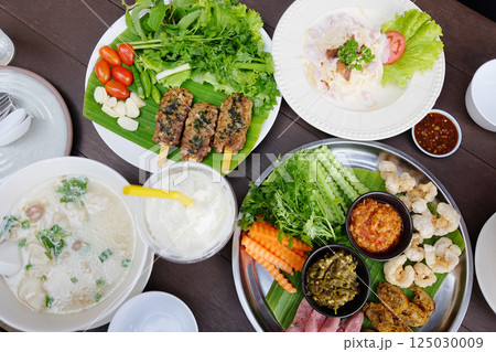 Northern Thai spicy green chilli dip with sausage and crackling with vegetable set on banana leaf. Minced pork porridge is traditional Thai food Northern Thai spicy green chilli dip with sausage and crackling with vegetable set on banana leaf. Minced pork porridge is traditional Thai food 125030009