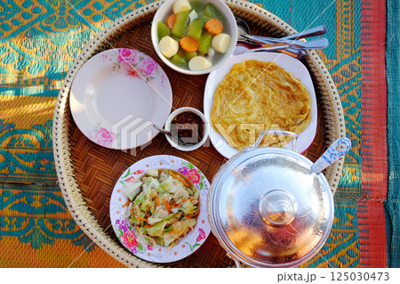 Scrambled egg with stir-fried cabbage and hot steamed rice with Tofu soup and chili sauce on woven basket at homestay. Thai food traditional breakfast or dinner in Thailand Scrambled egg with stir-fried cabbage and hot steamed rice with Tofu soup and chili sauce on woven basket at homestay. Thai food traditional breakfast or dinner in Thailand 125030473