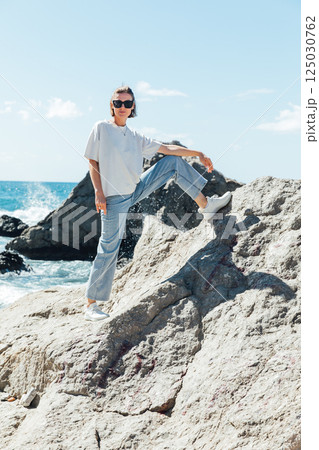 Beautiful woman in summer clothes walking on the beach by the sea Beautiful woman in summer clothes walking on the beach by the sea 125030762
