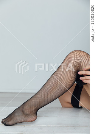 Woman wearing black tights stockings on slender long legs on a white background Woman wearing black tights stockings on slender long legs on a white background 125030826