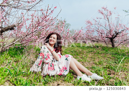 woman smiling in flower dress in spring blooming garden 125030843