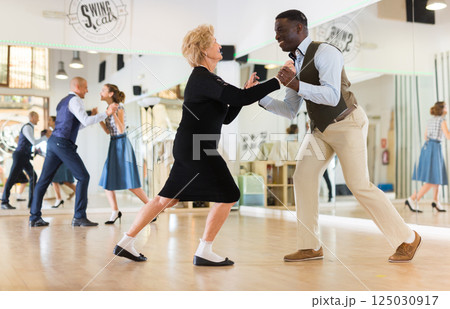 Lady learning to dance lindy hop with man in dance school Lady learning to dance lindy hop with man in dance school 125030917