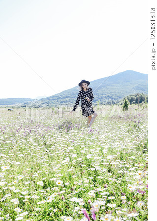 woman in dress walking with flowers in a field of daisies woman in dress walking with flowers in a field of daisies 125031318