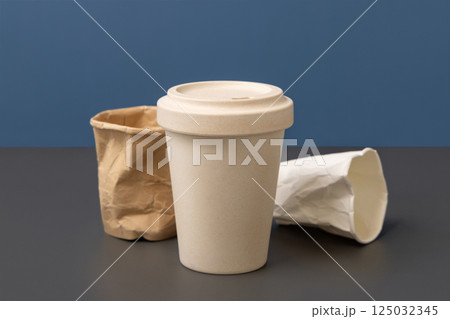 Used disposable paper cups and reusable bamboo coffee cup closeup, copy space, mockup 125032345