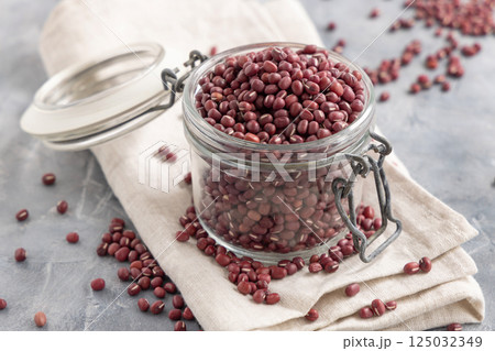 Glass jar full of azuki beans on gray closeup. Dried uncooked legumes. Vegetarian protein 125032349