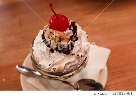 close up of Sundae cream ice cream with cherry on top and chocolate sauce with a tea spoon 125032461