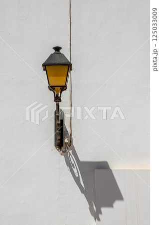 Lantern with its shadow on a white wall, Spain 125033009