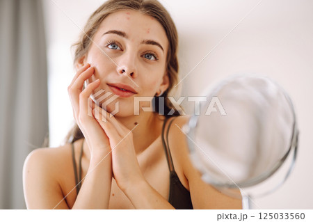 Woman worry about her face when she saw the problem of acne occur by a mini mirror. Pimples, acne Woman worry about her face when she saw the problem of acne occur by a mini mirror. Pimples, acne 125033560