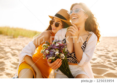 Two beautiful women enjoying on the beach. Female friends walking on the beach. Lifestyle concept. 125033954