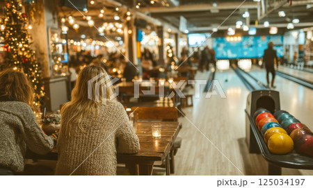 Festive bowling alley with people dining and celebrating, warm lights and a cozy holiday atmosphere 125034197