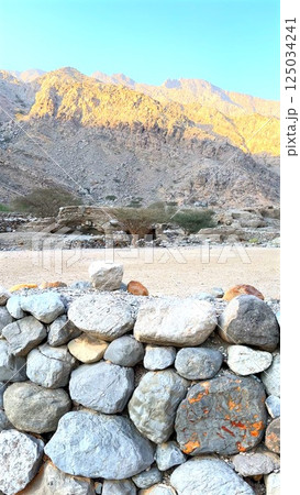 Rugged village with ancient caves carved into rocky hills. Stone walls stand against time, preserving cultural history. Remote landscape reveals heritage of early civilization. Rugged village with ancient caves carved into rocky hills. Stone walls stand against time, preserving cultural history. Remote landscape reveals heritage of early civilization. 125034241