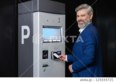 Man paying parking fee using card at automatic machine Man paying parking fee using card at automatic machine 125034715