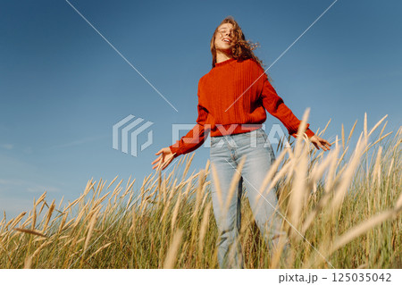 Beauty woman enjoying nature outdoors in grass. Calmness and tranquility. Travel, tourism concept. Beauty woman enjoying nature outdoors in grass. Calmness and tranquility. Travel, tourism concept. 125035042