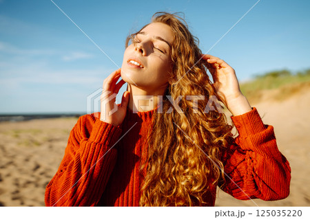 Outdoor portrait of pretty woman on the beach in cold sunny weather. Travel, fashion, blogging 125035220