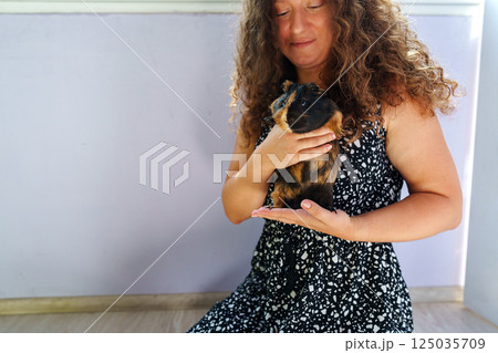 Woman enjoys quality time with her guinea pig in a cozy indoor setting during the afternoon 125035709